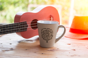 coffee cup and ukulele on wooden table
