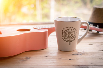 coffee cup and ukulele on wooden table
