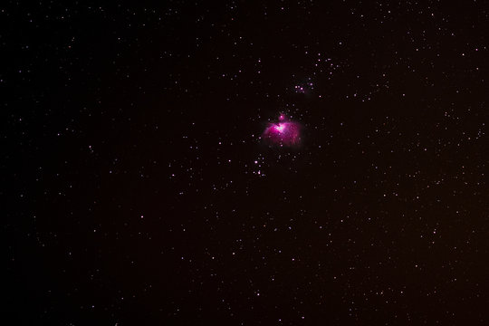the pink Orion Nebula in the starry night sky