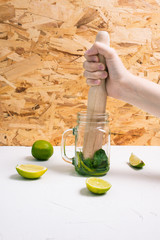 Girl squeezes juice from lime to make mojito. Mixing peppermint and lime. A refreshing summer...