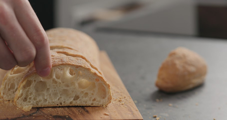 man hand touching ciabatta slices on olive board