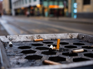 A few old and used cigarette stubs left on a public trash bin outside in the UK