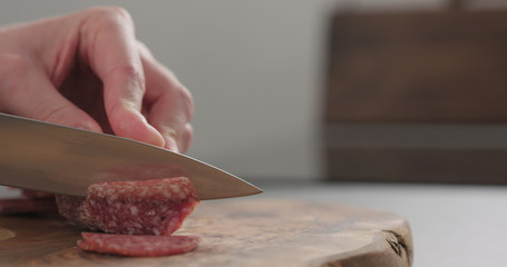 slicing italian salame on wood board with copy space