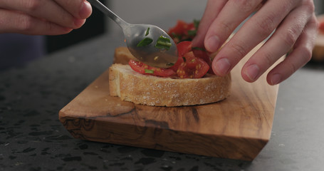 making bruschetta with cherry tomatoes and spinach leaves