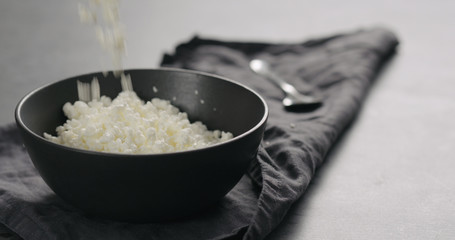 cottage cheese falling into black bowl closeup