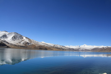 yandrok lake the fresh water lake in tibet surround with snow mountain and blue sky .relecction of snow mountain in yamdrok lake