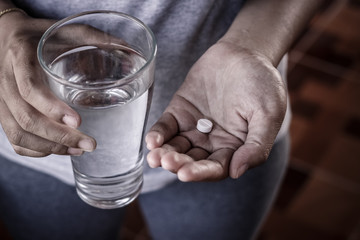 Close up of girl holding paracetamol and glass of water. - obrazy, fototapety, plakaty