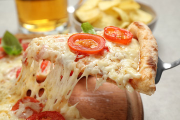 Taking slice of delicious pizza Margherita at table, closeup