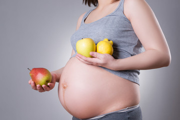 Pregnancy and nutrition - pregnant woman with fresh fruit on gray background