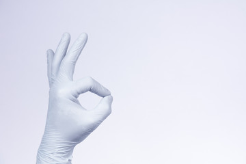 Fototapeta premium Ok sign is showed by left man hand in a white medical glove on a white background. Okay. All right