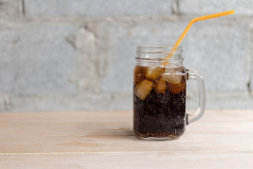 cola with ice in glass on wood table