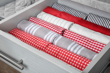 Open drawer with folded towels, closeup. Order in kitchen