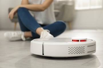 Fototapeta premium Woman using robotic vacuum cleaner at home