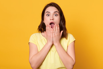 Close up portrait of astonished woman with widely open mouth, being amazement, stands with big...