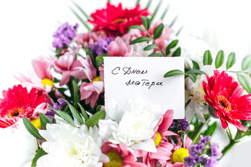 white card for a bouquet with the inscription Happy Mother's Day in russian in a bright beautiful bouquet of flowers