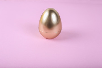 Golden egg on pink background, close up