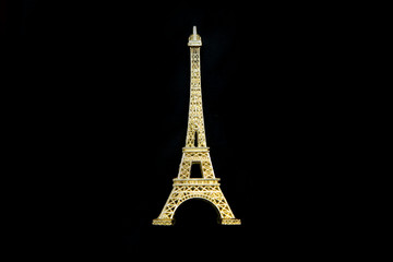 Fototapeta na wymiar The small golden Eiffel tower as a souvenir from Paris. Isolated on a black background. 