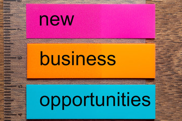 Three bookmark stickers with the words new business opportunities, on a dark natural wooden table