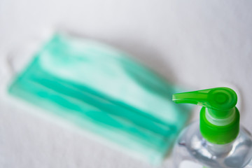 Hand sanitizer bottle with surgical mask in blur background. General personal protective equipment for use in virus diseases outbreak or pandemic, such as covid-19 and filovirus.
