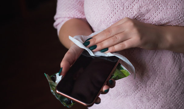 Woman hold and disinfection of the phone with antiseptic agents 