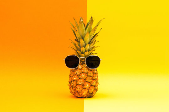 Pineapple with sunglasses on a orange and yellow background