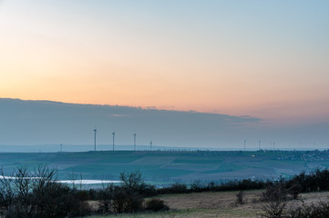 Fototapeta na wymiar wind turbines in a hilly landscape at dusk