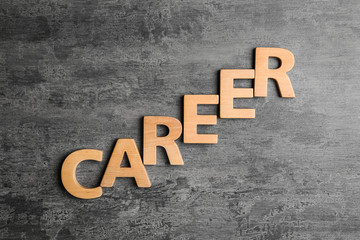Fototapeta premium Word CAREER made with wooden letters on grey stone background, flat lay