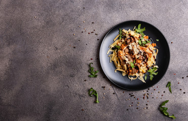 Bolognese pasta with mushrooms and arugula poured balsamic sauce on a grey background. Copy space for text.