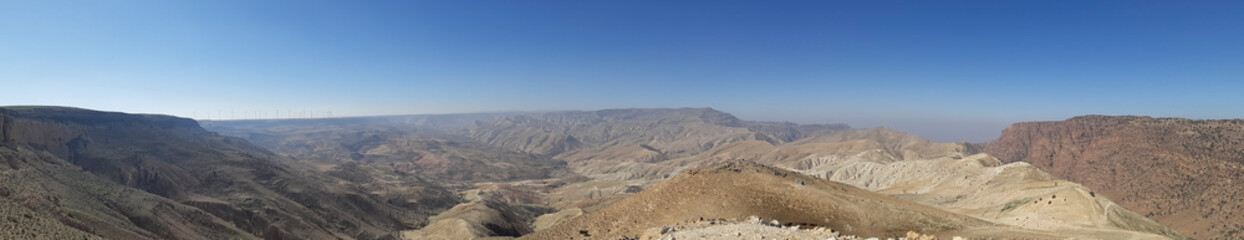 Fototapeta na wymiar Panorama of Jordanian nature landscape at Tafilah Governorate, looking to Ma'an governorate in Dana neighborhood. Wind farm in the far distance. 