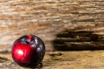 Fresh fruits of red plum (Prunus domestica) on aged wooden background