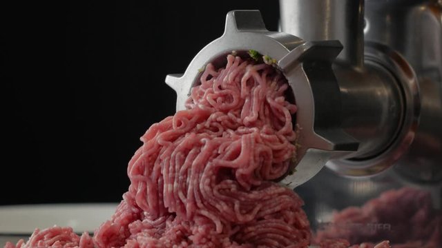 Meat grinding process, meat mincing in black background