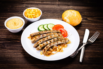 Grilled sausages and vegetables on wooden table