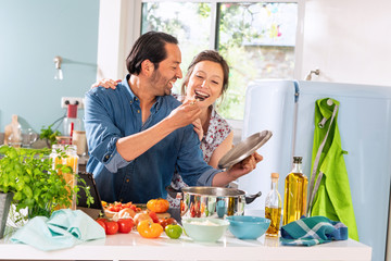 Obraz na płótnie Canvas Cheerful Couple in the kitchen preparing an Italian sauce