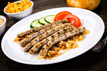 Grilled sausages and vegetables on wooden table