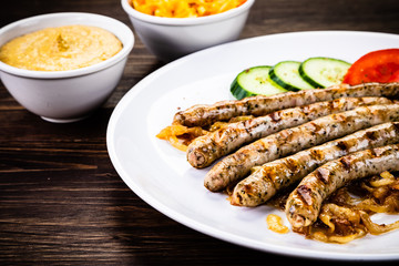 Grilled sausages and vegetables on wooden table