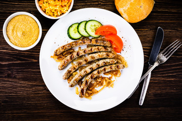 Grilled sausages and vegetables on wooden table