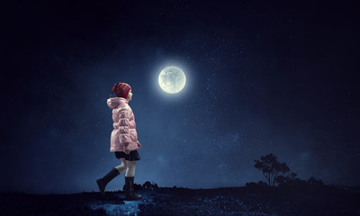 A little girl walks on a beautiful full moon night.