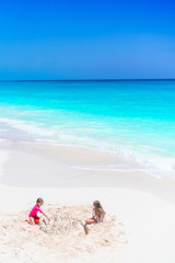 Two little happy girls have a lot of fun at tropical beach playing together
