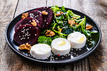  Beetroot salad with goat cheese on wooden background