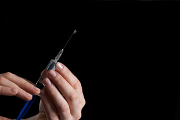 syringe for injection with medicine in hands on a black background