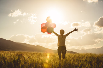 Cheering young asian woman on grassland with colored balloons - obrazy, fototapety, plakaty