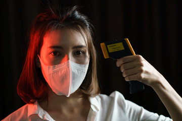 Woman  feeling sick wearing protective mask, hand use digital thermometer checking temperature.