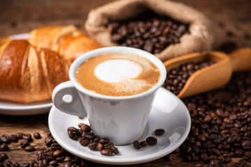 A cup of cappuccino with coffee bean as background.