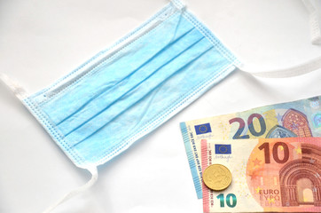 Surgical mask next to euro money on white background