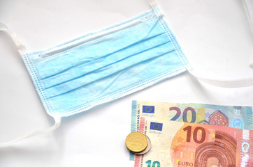 Surgical mask next to euro money on white background