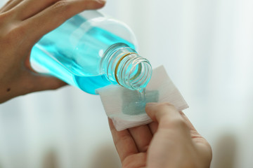Pouring ethyl alcohol from bottle  into a cotton piece for corona virus or Covid-19 protection.