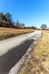 Old asphalt road near field. Czech landscape. Country road near the forest. Spring morning on country road.
