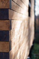 A newly built log house is lit by the sun. Fragment of the house in the photo