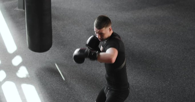 Boxer man in gloves making blows training boxing in gym, top view. Sportsman having cardio training in sport club. Sportive guy on workout, top view. Professional sport concept. Practicing punches.