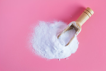 baking soda in wooden spoon on pink background